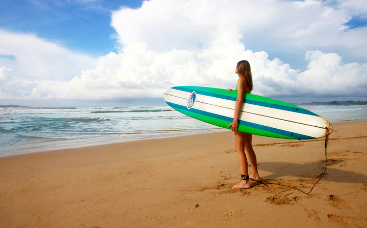 Woman holding a surf board before entering the water wondering what the best bikini for surfing is